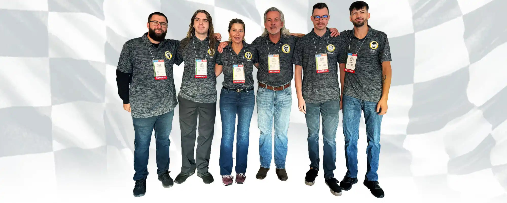 Group of people wearing matching gray shirts and jeans standing together.
